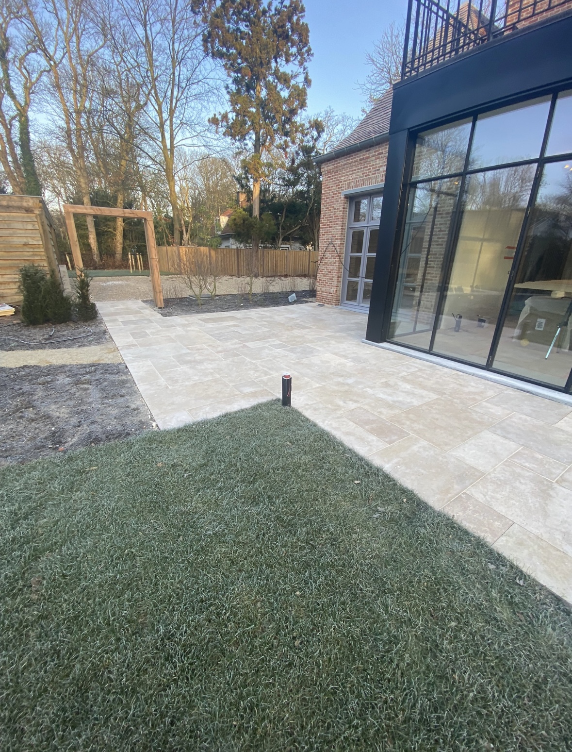 Nieuw aangelegd gazon en natuurstenen terras bij een moderne villa