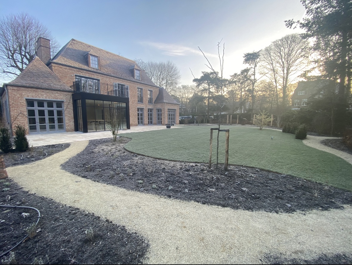 Grote villatuin met slingerend grindpad, gazon en nieuwe borders
