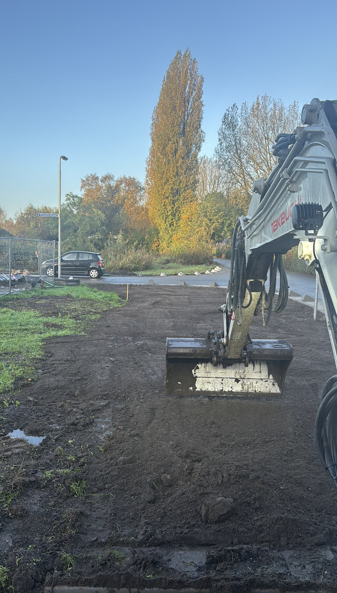 Graafmachine met egalisatiebak maakt een kavel vlak