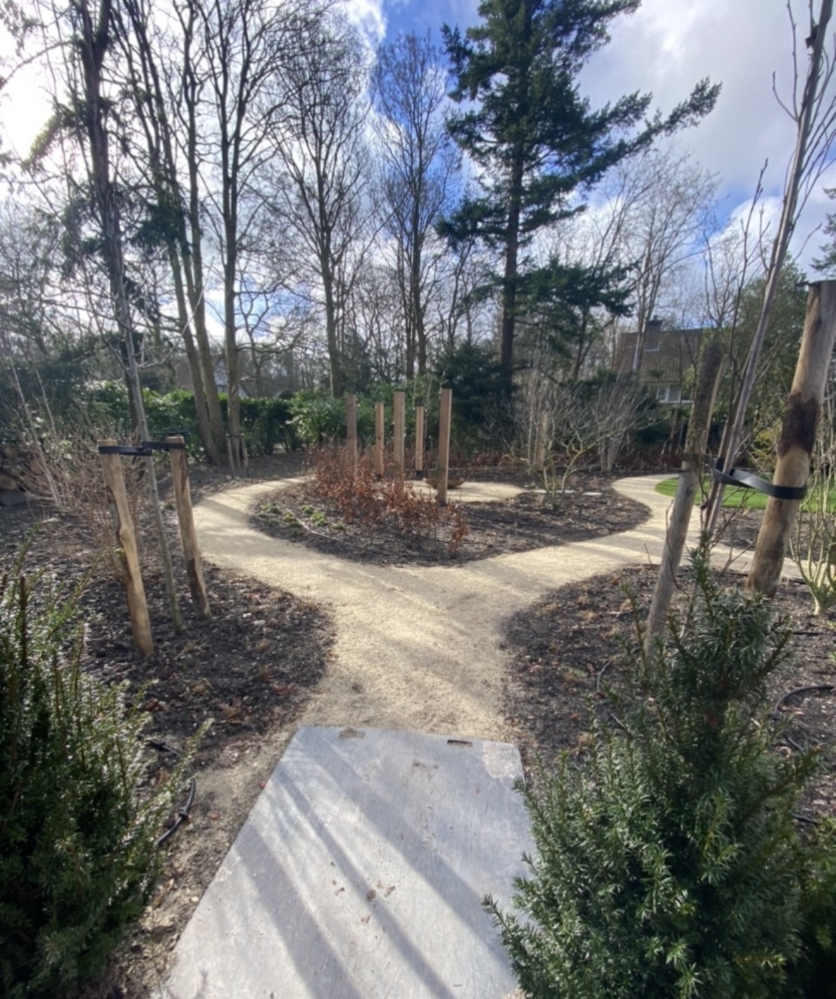 Aangelegde tuin met slingerende grindpaden, nieuwe hagen en jonge bomen