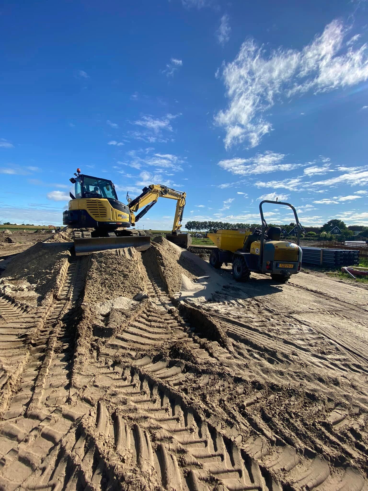 Eigen graafmachine en dumper op een zandkavel